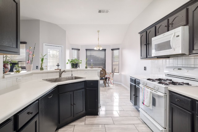 kitchen with lofted ceiling, white appliances, sink, pendant lighting, and a chandelier