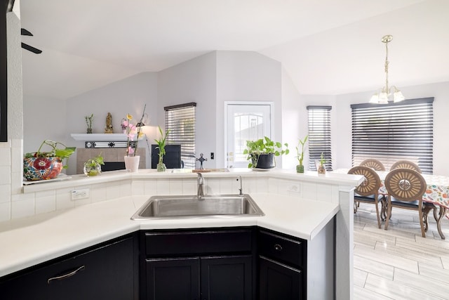 kitchen featuring light hardwood / wood-style floors, decorative light fixtures, sink, lofted ceiling, and kitchen peninsula