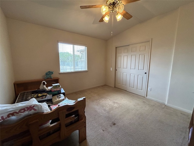 bedroom with ceiling fan, a closet, vaulted ceiling, and light colored carpet