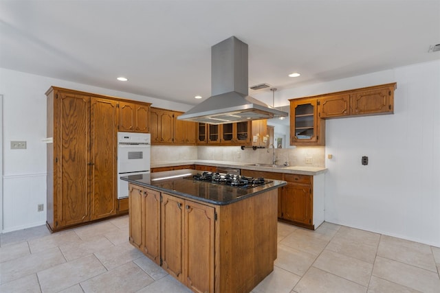 kitchen with a kitchen island, decorative backsplash, sink, island range hood, and stainless steel gas stovetop