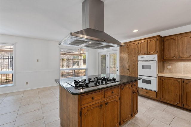 kitchen with gas cooktop, tasteful backsplash, island range hood, double oven, and a center island