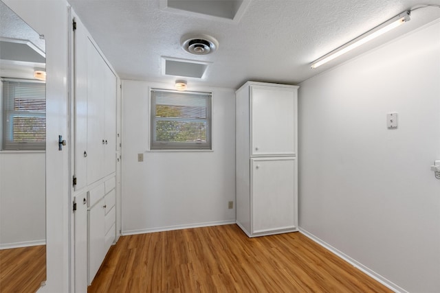 hall featuring light wood-type flooring and a textured ceiling