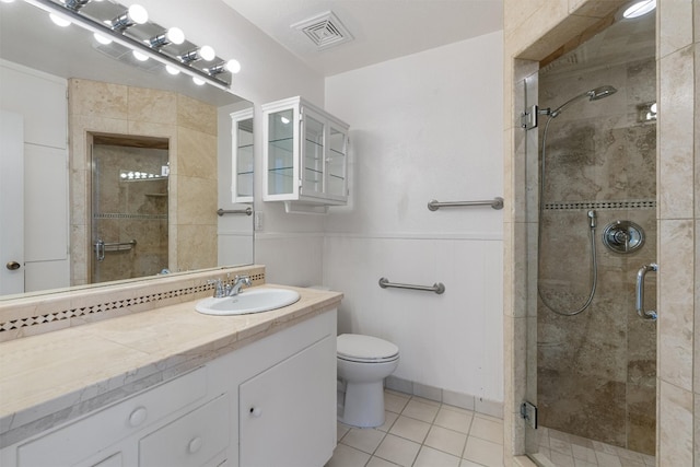 bathroom with tile patterned floors, vanity, a shower with door, and toilet