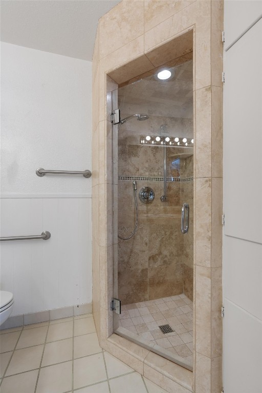 bathroom with a shower with door, tile patterned floors, and toilet