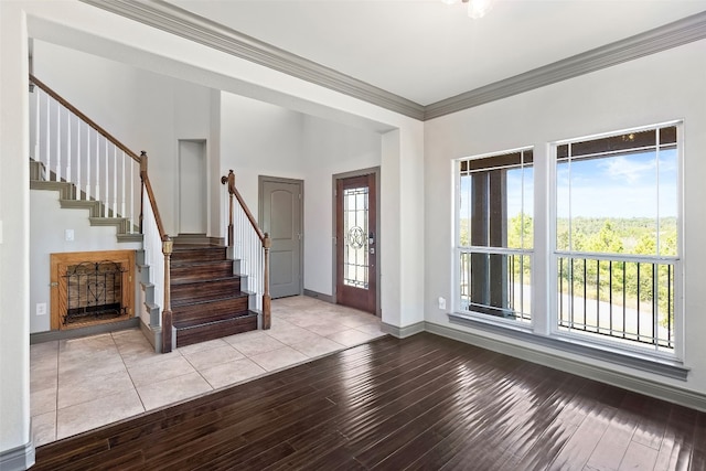 foyer with plenty of natural light, ornamental molding, and light wood-type flooring