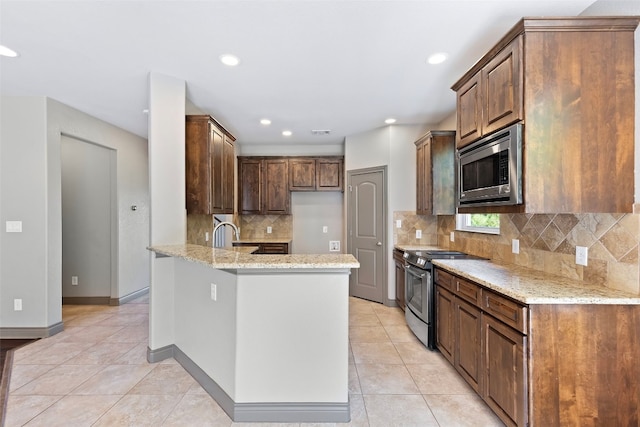 kitchen with light stone countertops, kitchen peninsula, stainless steel appliances, and light tile patterned flooring