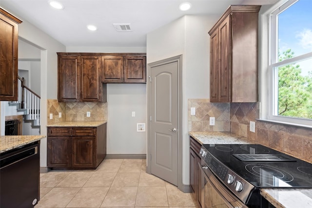 kitchen featuring light stone countertops, tasteful backsplash, black appliances, and light tile patterned floors