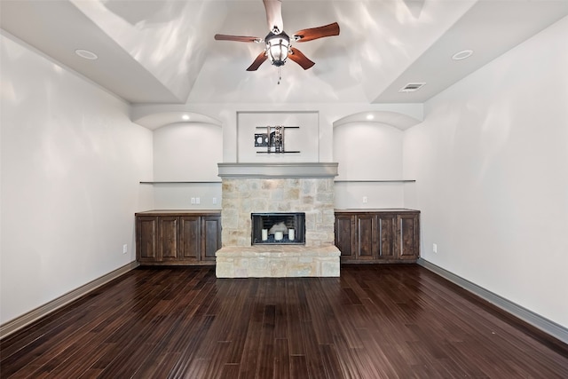 unfurnished living room featuring a stone fireplace, lofted ceiling, dark wood-type flooring, and ceiling fan