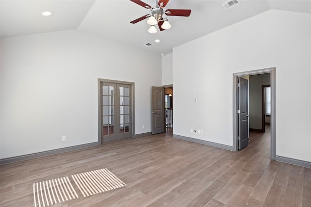 spare room featuring light hardwood / wood-style flooring, french doors, high vaulted ceiling, and ceiling fan