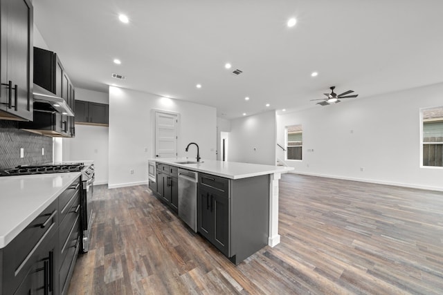 kitchen with stainless steel appliances, sink, dark hardwood / wood-style flooring, and an island with sink