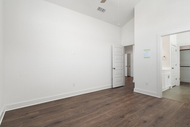 unfurnished bedroom with dark wood-type flooring, ceiling fan, high vaulted ceiling, and connected bathroom