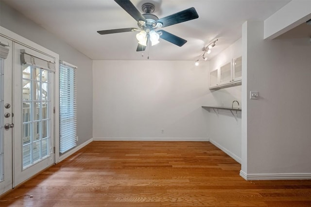 unfurnished dining area with a ceiling fan, light wood-type flooring, and baseboards