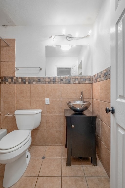 bathroom with tile walls, tile patterned floors, vanity, and toilet