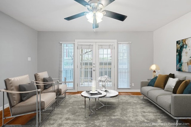 living room with ceiling fan, baseboards, and wood finished floors