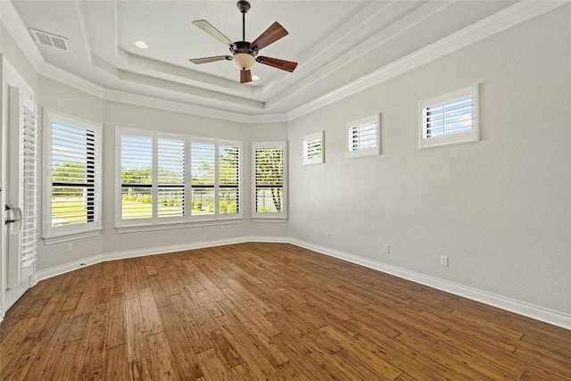 spare room featuring ceiling fan, wood finished floors, visible vents, baseboards, and a raised ceiling