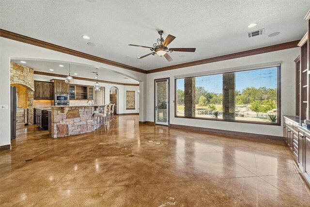 unfurnished living room with tile patterned floors, ceiling fan, a textured ceiling, and ornamental molding