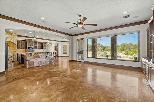 unfurnished living room with arched walkways, a textured ceiling, visible vents, baseboards, and crown molding