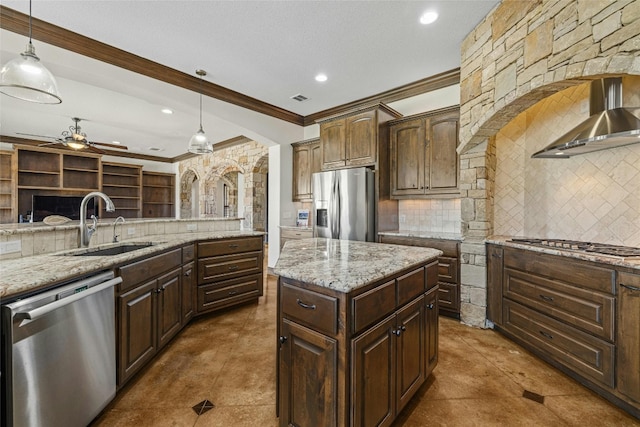 kitchen with stainless steel appliances, wall chimney exhaust hood, decorative light fixtures, and a center island