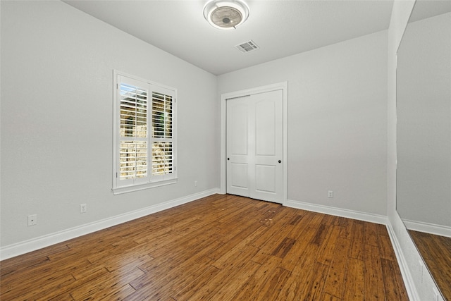 interior space with dark wood-type flooring, visible vents, and baseboards