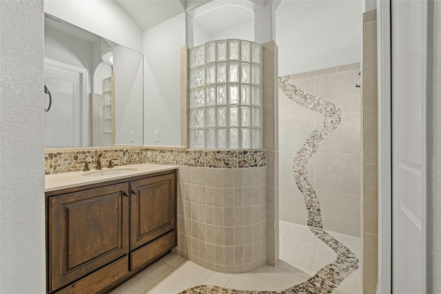 bathroom featuring tile patterned floors, vanity, tiled shower, and tile walls