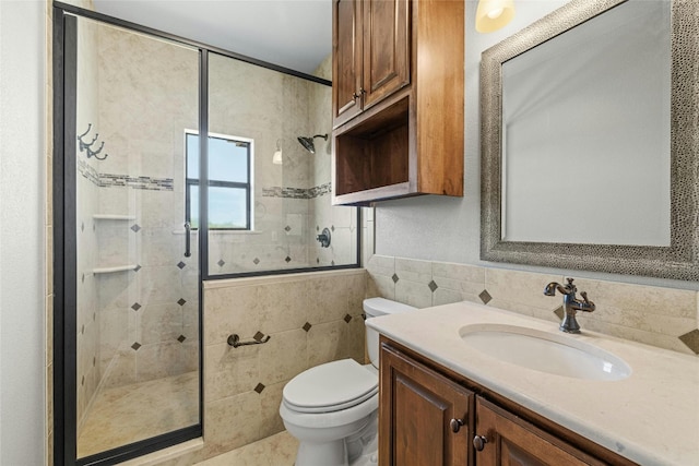 bathroom featuring toilet, a stall shower, vanity, and tile walls