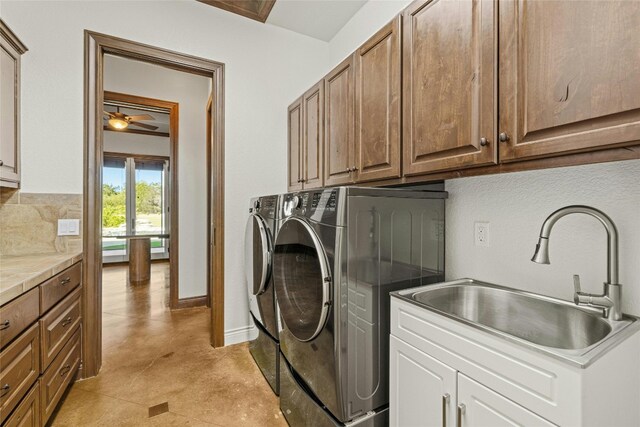 laundry room with ceiling fan, cabinets, sink, and washing machine and dryer