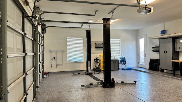 exercise room with a garage and baseboards