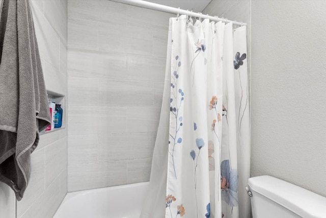 bathroom featuring toilet and shower / tub combo with curtain