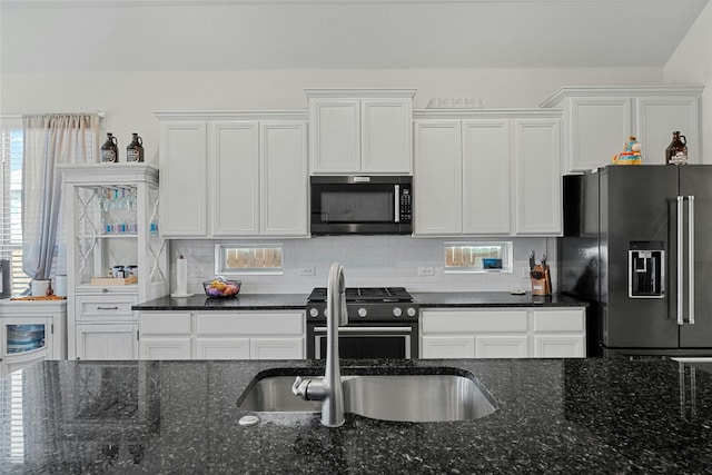 kitchen with dark stone countertops, sink, decorative backsplash, appliances with stainless steel finishes, and white cabinetry