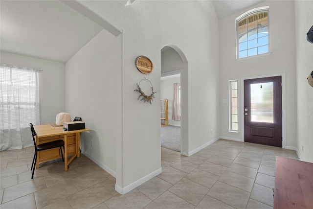 entrance foyer featuring light tile patterned flooring and high vaulted ceiling