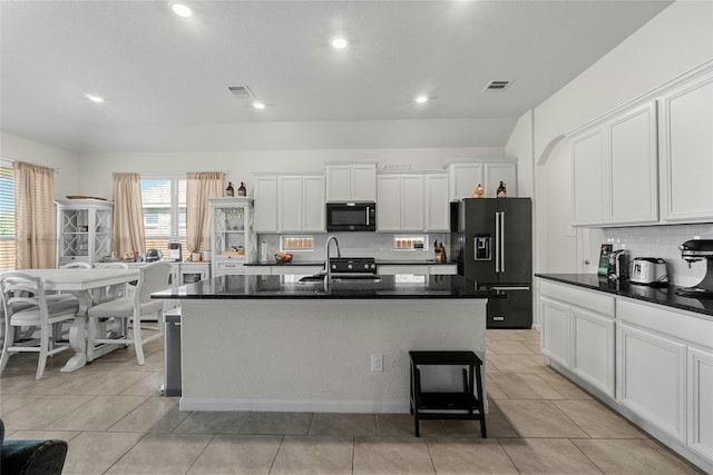 kitchen with white cabinets, a kitchen island with sink, decorative backsplash, and black appliances