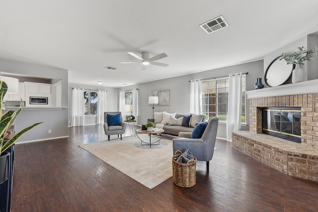 living room with a fireplace, dark hardwood / wood-style floors, and ceiling fan