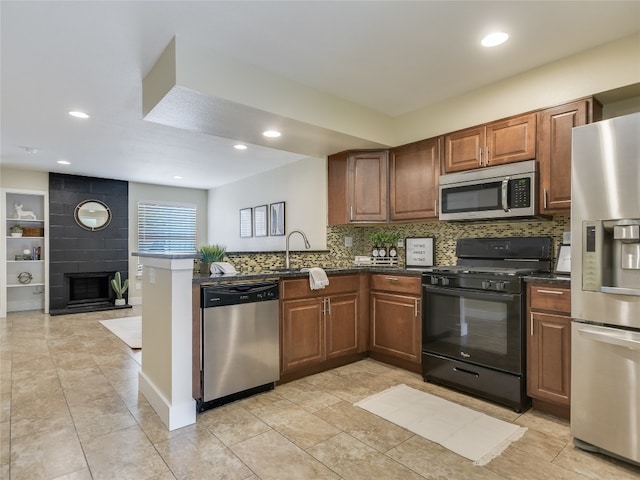 kitchen with appliances with stainless steel finishes, a fireplace, kitchen peninsula, and tasteful backsplash