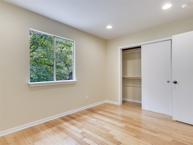 unfurnished bedroom with light hardwood / wood-style flooring and a closet