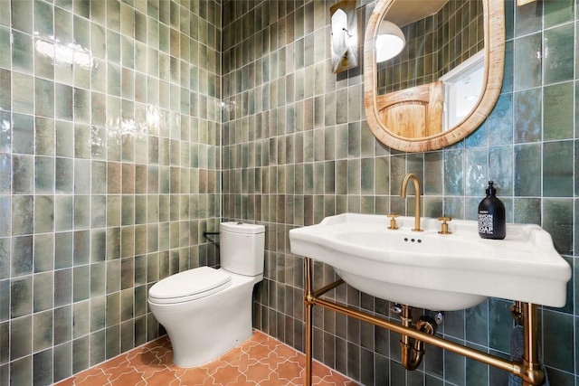 half bath featuring toilet, a sink, and tile walls