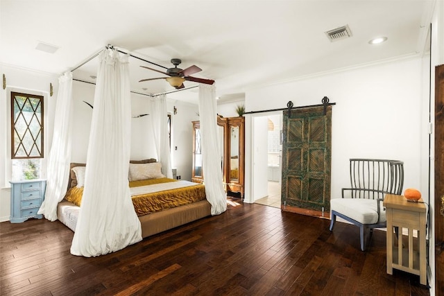 bedroom featuring a barn door, recessed lighting, dark wood-type flooring, visible vents, and crown molding