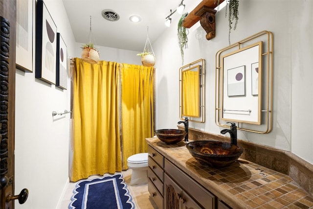 full bathroom featuring visible vents, a sink, toilet, and double vanity