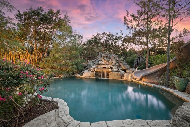 pool at dusk with a water slide