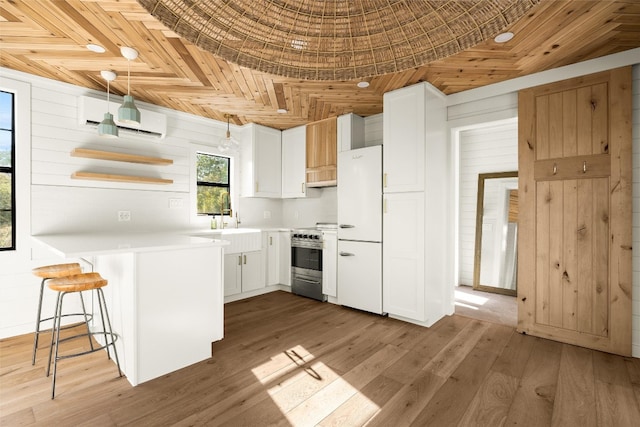 kitchen featuring a sink, white cabinets, an AC wall unit, light countertops, and high end stainless steel range