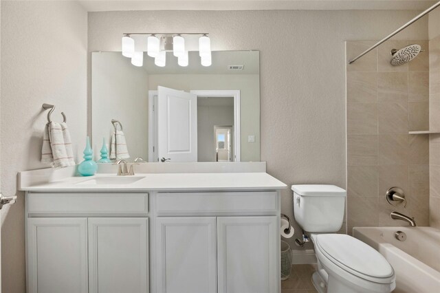 bathroom with visible vents, a textured wall, toilet, vanity, and washtub / shower combination