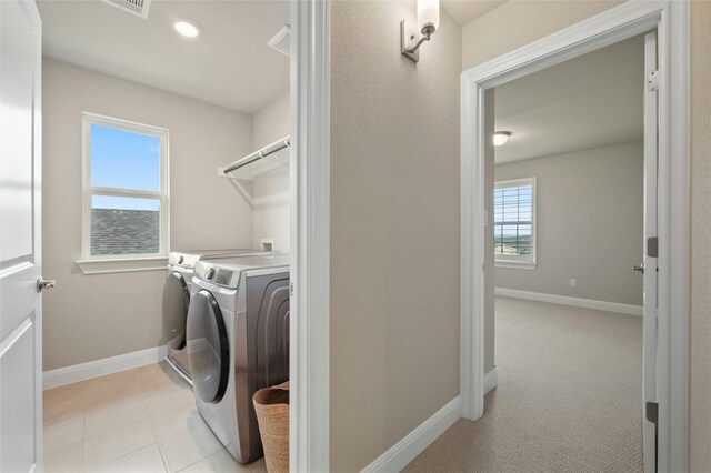 washroom with laundry area, light tile patterned flooring, washer and clothes dryer, and baseboards