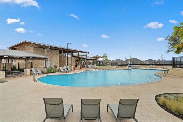 community pool with a patio area and fence