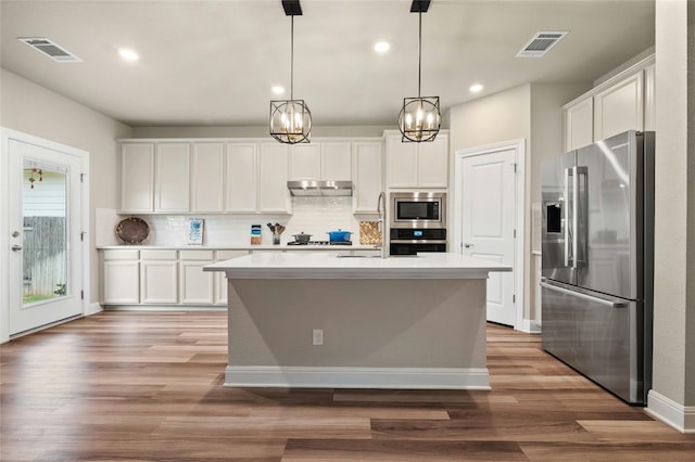 319 Victoria Peak Loop, Dripping Springs, TX 78620 - kitchen with under cabinet range hood, white cabinets, stainless steel appliances, and visible vents