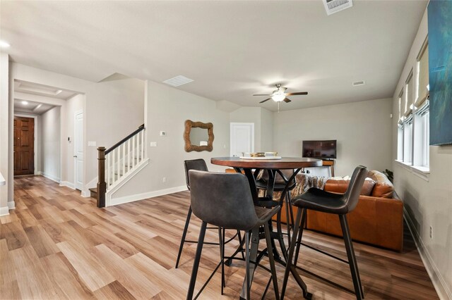 dining area featuring light wood-type flooring, visible vents, baseboards, and stairs