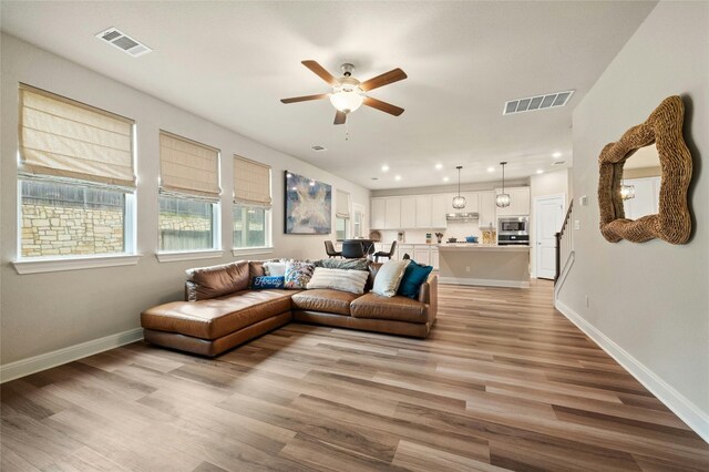 living area featuring baseboards, visible vents, and light wood-style floors