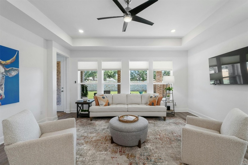 living room featuring a tray ceiling, ceiling fan, and hardwood / wood-style floors