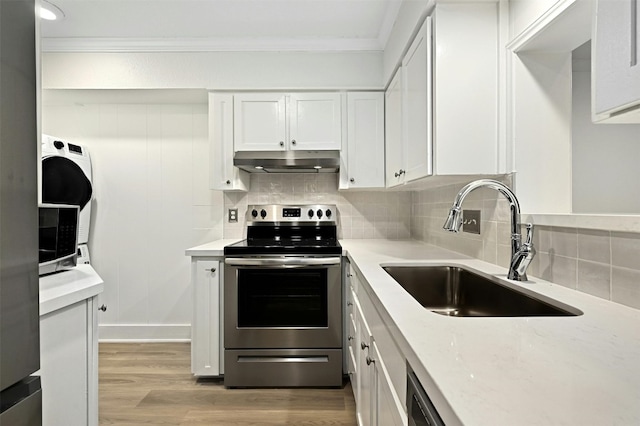 kitchen featuring light wood-type flooring, stainless steel appliances, sink, white cabinetry, and backsplash