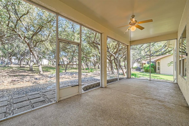 unfurnished sunroom featuring ceiling fan and a healthy amount of sunlight