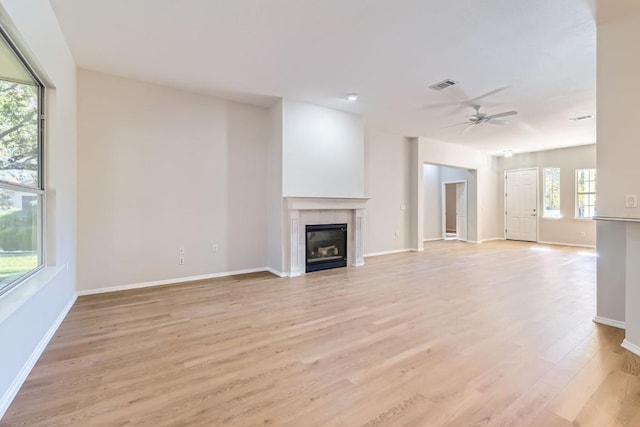 unfurnished living room with light hardwood / wood-style flooring, ceiling fan, and a tiled fireplace