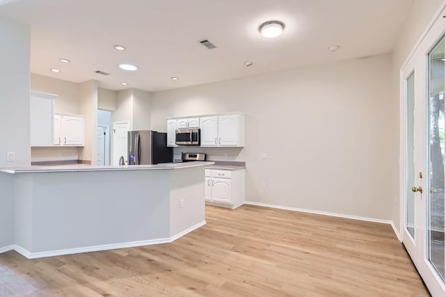 kitchen with kitchen peninsula, light wood-type flooring, white cabinetry, and stainless steel appliances